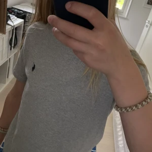 Grå t-shirt från Polo Ralph Lauren - Klassisk grå t-shirt från Polo Ralph Lauren med liten broderad logga på bröstet. Modellen är 12 år och 153cm .