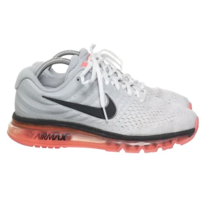 Nike Air Max sneakers i vitt och korall - Nike Air Max sneakers i vitt med svart swoosh och korallfärgad sula. Ovandelen är i ventilerande syntetmaterial och skorna har klassisk snörning. Perfekta för dig som gillar sportig stil och vill ha bekväma skor med dämpning. Skorna är i nyskick 