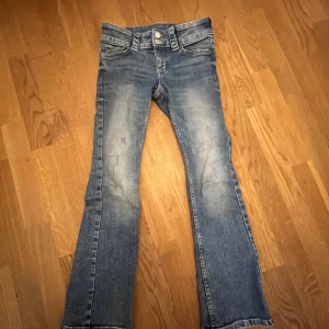 Blå bootcut jeans från H&M - Säljer ett par blå bootcut jeans från H&M med låg midja. Jeansen har fickor fram och bak samt knäppning med dragkedja och knapp. Köptes på slutet av sommaren 2024