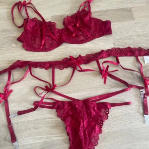 Vinröd babydoll-nattlinne med spets och volang - Supersöt vinröd babydoll med spets upptill, smala axelband och en stor rosett framtill. Volangdetaljer längs framsidan och nederkanten ger en romantisk känsla. Perfekt för dig som vill känna dig extra fin hemma.