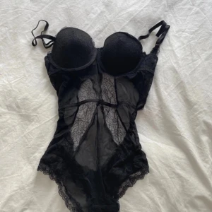 Svart spetsbody från Hm - Säljer en helt ny svart body från Hm med bygel och vadderade kupor. Bodyn har transparent spetsdetaljer framtill och baktill samt justerbara axelband. priset kan självklart diskuteras vid snabbt köp