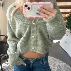 Grön/grå  kofta med pärlknappar - Säljer denna gosiga grön/grå stickade koftan med fina pärlknappar. Nypris: 900kr, knappt använd