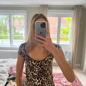 Leopardmönstrad topp från Nelly - Säljer en snygg leopardmönstrad topp från Nelly med korta ärmar och figurnära passform. Toppen har en djup, rundad ringning och är i stretchigt, tunt material som sitter skönt på kroppen. Perfekt för dig som vill sticka ut lite extra.
