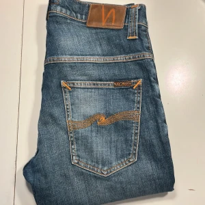 Blå jeans från Nudie Jeans, W31 L34 - Snygga blå jeans från Nudie Jeans med oranga sömmar. Modellen har raka ben och normal passform. Perfekt för dig som gillar stilrena jeans. Pris kan diskuteras vid snabb affär🙌🏼 skriv om ni funderar över något.‼️OBS. Jensen ser ljusare ut en va de är på bild 1/2‼️ 