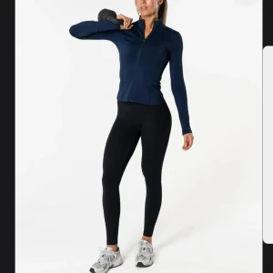 Marinblå träningsjacka från Relode - Snygg marinblå träningsjacka från Relode med slim passform och hel dragkedja framtill. Jackan har hög krage och långa ärmar, perfekt för gymmet eller löprundan. Ny och endast provad. Strl M men passar mig som har S i vanliga fall.