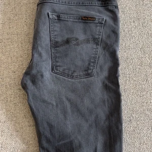 Mörkgrå jeans från Nudie Jeans - 🧵 Märke: Nudie jeans (grim Tim) 📏 Storlek: 32/34 ✨ Skick: Mycket gott skick / Nästan som nya 🎯 Perfekta både till vardags och när du vill klä upp dig lite extra 📦 Snabb leverans – skickas samma dag! 💌 Har du frågor? Hör gärna av dig – svarar snabbt!