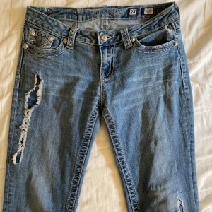 Miss Me ljusblå bootcut jeans🤍 - Säljer ett par ljusblå jeans från Miss Me med snygga slitningar på låret och detaljerade bakfickor med broderade kanter! Modellen är bootcut med låg midja och är i in princip ny skick🫶🏼(de vita fläckarna var där när jag köpte dom men de märks knappt!). Hör av dig om du har någon!  💭nypris: 1200kr