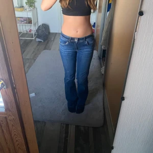Blå bootcut jeans med låg midja - Säljer ett par snygga blå jeans med bootcut-modell och låg midja, jeansen är gjorda i ett stretchigt denimtyg som sitter skönt. 