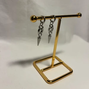 Silvriga örhängen med kedja och spikes - Coola silvriga örhängen med små kedjor och spetsiga spikes som hänger ner. Perfekt för dig som gillar edgy och modern stil. Örhängena är i metall och har en minimalistisk design med runda länkar och konformade detaljer.
