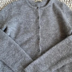 Grå kofta med knappar från Gina tricot  - Mysig grå kofta från Gina tricot. Långärmad och normal passform, perfekt att slänga på över en t-shirt eller linne. Enkel och stilren design som funkar till allt. Perfekt nu till hösten! Nypris 400kr