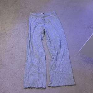 Grå ribbade mjukisbyxor - Grå ribbade mjukisbyxor från 157 i storlek XS. Byxorna har dragsko i midjan, vida ben och råa kanter nertill för en chill vibe. Perfekta för en avslappnad look eller när du bara vill vara bekväm hemma.