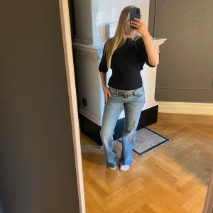 Svart t-shirt med knyt från Nelly - Svart t-shirt från Nelly i storlek S. Modellen har korta ärmar och en cool öppen rygg med knytband som ger en snygg detalj. T-shirten är croppad och har en rund halsringning. är det mycket bra skick då jag bara använt den två gånger 🩷