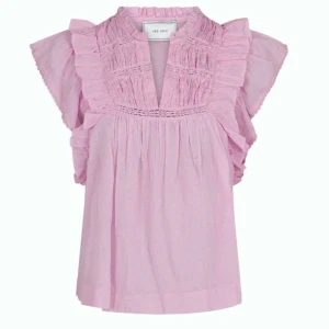 Ljusrosa blus med volang från Neo Noir - Supersöt ljusrosa blus från Neo Noir med volangdetaljer på axlarna och längs bröstet. 💗Blusen har v-ringning, korta ärmar och är tillverkad i ett lätt, luftigt bomullstyg. 💗 Orginella priset: 599kr 💗 Skicka för fler bilder! Lämna gärna prisförslag! 