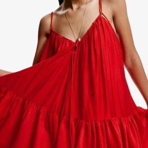 Röd omlottklänning med volang - Säljer en röd omlottklänning från H&M i storlek S. Klänningen har tunna axelband, volangdetaljer och en luftig, flowy passform. Perfekt för dig som gillar färgstarka och bekväma plagg med lite extra rörelse i tyget. Använd 1 gång