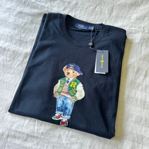 Ralph Lauren Bear T-shirt  - Ralph Lauren T-shirt i Nyskick aldrig använd. Prislapp sitter kvar. Storlek XL axelbredd: 46cm Längd: 76cm. Har du frågor angående tröjan eller passar inte priset så lägg ett meddelande🙌