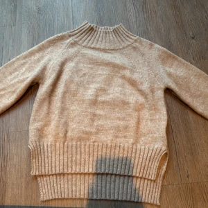 Beige stickad polotröja från Shein - Säljer en beige stickad polotröja från Shein i storlek S. Tröjan har en hög ribbad krage och breda ribbade muddar vid nederkant och ärmslut. Perfekt för dig som gillar en enkel och clean look med lite oversized känsla.