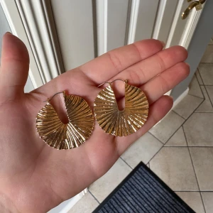 Guldiga platta örhängen med struktur - Säljer ett par runda men platta örhängen med struktur från Gina Tricot. De är använda en gång så därför i mycket bra skick. Hör gärna av dig vid frågor💗