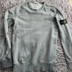 Grå sweatshirt från Stone Island - Säljer en stilren grå sweatshirt från Stone Island med klassisk rund hals och långärmad passform. 