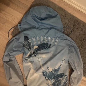 Trapstar windbreaker - Snygg ljusblå vindjacka från Trapstar med stor huva och dragsko. Endast 2 månader sen köp, Inga fläckar på den.
