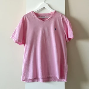Polo Ralph Lauren rosa t-shirt - Ny och oanvänd rosa t-shirt från Polo Ralph Lauren med blå logotyp på bröstet. Storlek XL. 100% bomull. Utan defekter.  Nypris: 1000kr