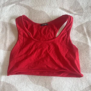 Röd linnetopp från Zentex - Snygg röd linnetopp från Zentex med sportig racerback-design. Toppen är ärmlös och har en croppad passform som passar perfekt till jeans eller shorts. Tillverkad i mjuk bomull som känns skön mot huden. Enkel och stilren look som funkar året runt.