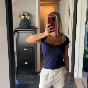 Mörkblå t-shirt med v-ringning - Säljer en enkel och snygg mörkblå t-shirt med v-ringad hals och korta ärmar. Toppen har en slim passform och är gjord i mjuk bomull, perfekt för en chill och avslappnad stil. Passar dig som gillar basic men ändå vill ha lite edge.