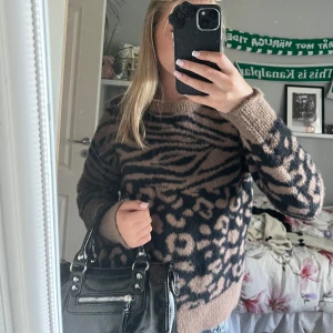 Beige och svart stickad leopardtröja - Säljer en fluffig stickad tröja i beige och svart med leopard- och zebramönster. Tröjan har rund hals och långa ärmar, perfekt för dig som gillar djurmönster och vill ha en mysig vibe. Passar till jeans eller kjol för en cool look. säljer för den ej kommer till användning❤️