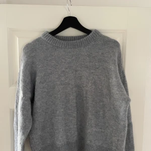 Blå stickad tröja från Bik Bok - Mysig blå stickad tröja från Bik Bok i storlek XS. Tröjan har en rundad hals med bred ribbad kant och långa ärmar. 