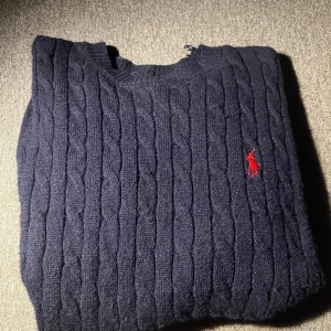 Mörkblå kabelstickad tröja Ralph Lauren - Den är fke men fortfarande väldigt hög kvalitet. Det står XXL på taggen men den passar mer som M. Den hade ett mindre hål på axeln som jag har sytt igen, vilket inte märks då tröjan sitter på.