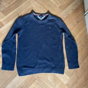 Mörkblå tröja Tommy Hilfiger - Snygg mörkblå tröja från Tommy Hilfiger med diskret logga på bröstet. Rund halsringning med ribbade muddar vid ärmslut och nederkant. Perfekt för dig som gillar klassisk stil och vill ha något som funkar till jeans eller chinos.