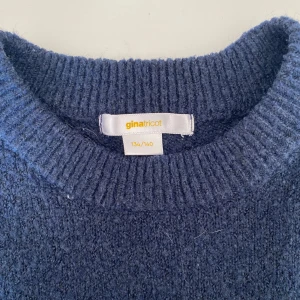 Mörkblå stickad tröja Gina Tricot - Mysig mörkblå stickad tröja från Gina Tricot med rund hals och ribbade muddar vid ärmslut och nederkant. Perfekt för kyliga dagar och enkel att matcha med jeans eller kjol. Klassisk och stilren modell som passar dig som gillar enkelhet.