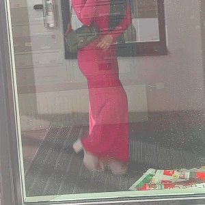 Rosa långklänning från Boohoo - Säljer en snygg långklänning i stark rosa från Boohoo. Klänningen har lång ärm och en fyrkantig urringning som ger en modern vibe. Materialet är mjukt och stretchigt, vilket gör att den sitter tight och följer kroppen. Perfekt för dig som gillar att sticka ut.