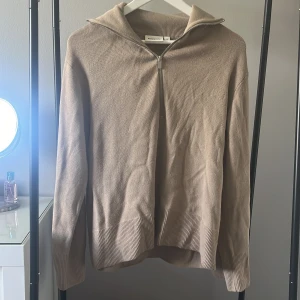 Beige stickad half zip tröja Kappahl - Säljer en beige stickad tröja från Kappahl i storlek S. Tröjan har en snygg half zip-dragkedja framtill och ribbade muddar vid ärmslut och nederkant. (Behövs strykas)