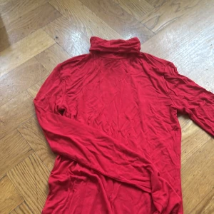 Röd polotröja från H&M XS - Säljer en röd polotröja från H&M i storlek XS. Tröjan har lång ärm och en hög krage som ger en chill och snygg look. Materialet är mjukt och stretchigt, perfekt för lager-på-lager under hösten och vintern. Passar dig som gillar enkel och stilren design.