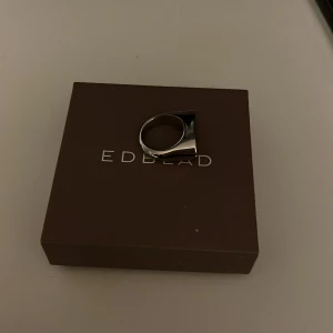 Silverfärgad ring från Edblad - Stilren och modern ring i silverfärg från Edblad. Ringen har en bred, platt ovansida som ger ett unikt och elegant utseende. Perfekt för att ge en minimalistisk touch till din stil. Har tyvärr inte kommit till användning🩷 kostade 499 vid köp.