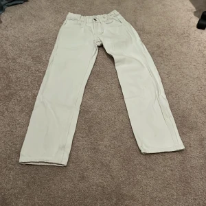 Vita byxor från Lindex - Snygga vita byxor från Lindex med elastisk midja och raka ben. Perfekta för en stilren look. Byxorna har fickor bak och en knapp framtill.