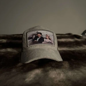 Grå keps Maggiore - Snygg grå keps med ett unikt tryck framtill. Kepsen har en klassisk design med nätmaterial på sidorna och justerbar passform. Perfekt för en avslappnad stil.  PRIS KAN DISKUTERAS VID SNABB OCH SMIDIG AFFÄR.