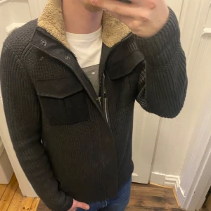 Grå stickad kofta teddyfoder - Säljer en grå stickad kofta med teddyfoder i kragen. Koftan har dragkedja och knappar framtill samt två stora bröstfickor. Storlek L men passar även som M. Han på bilden är ca 182,Tveka inte att kontakta vid eventuella frågor😀