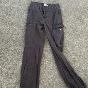 Svarta cargobyxor från Zara - Säljer ett par svarta cargobyxor från Zara med flera praktiska fickor och dragkedja. Byxorna har en avslappnad passform och är perfekta för en casual look. Tillverkade i ett slitstarkt material.