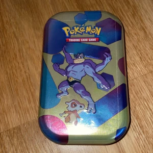 Pokémon Trading Card Game Tin 151 card made in USA - Säljer en Pokémon Trading Card Game plåtlåda med motiv av Machamp och Cubone. Perfekt för att förvara dina kort eller som samlarobjekt. Lådan har en färgglad design med blå, lila och guldiga nyanser. Köp direkt eller ge prisförslag! 💥