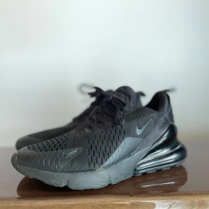 Svarta Nike Air Max 270 - Säljer mina snygga svarta Nike sneakers med en modern design och bekväm med smal passform. Skorna har snörning och en robust sula för extra komfort. Perfekta för både träning och vardagsbruk. Jag har bara använt dem 1 gång. Pris kan diskuteras vid snabb affär.