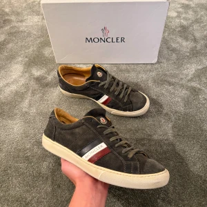 Moncler Skor - Tjena, säljer nu dessa riktigt feta Moncler skorna i storlek 42! De är i en mörkblå/grå mocka, perfekt till våren/sommaren! Skick: 8/10. Box och kvitto finns. Hör av dig vid minsta fundering!🌟💯