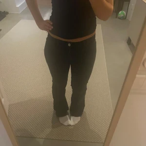 Svarta bootcut jeans - Snygga svarta bootcut jeans med låg midja och klassisk femficksdesign. Perfekta för en avslappnad stil. De har en knapp och dragkedja framtill.