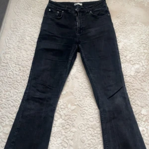 Svarta bootcut jeans från Gina tricot  - Säljer ett par svarta bootcut jeans med klassisk femficksdesign. Jeansen har en snygg mörk tvätt och sitter tajt upptill med utsvängda ben. Perfekta för dig som gillar en tidlös och cool look. Jeansen är mid-waist.