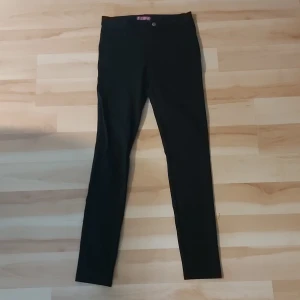 Svarta skinny byxor från Aqua - Svarta byxor från Aqua i skinny modell med hög midja. Tillverkade i en mjuk och stretchig mix av rayon och nylon som sitter tajt och bekvämt. Perfekta för dig som gillar en clean och stilren look.