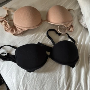 2-pack BH från H&M, svart & beige 70B - Säljer två klassiska BH:ar från H&M i storlek 70B. En är svart och en är beige, båda med släta kupor och justerbara axelband. Materialet är mjuk bomull med lite stretch och insida i polyester. Perfekta under alla toppar för en clean look. 120kr var.