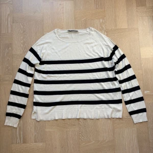 Randig stickad tröja - Säljer en snygg stickad tröja från Zara i storlek M. Tröjan är vit med svarta horisontella ränder, har lång ärm och rund halsringning. Mjukt och tunt material.