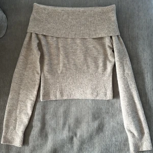 Beige offshoulder stickad tröja Weekday - Superfin beige stickad tröja från Weekday med bred ribbad kant och offshoulder-modell. Tröjan har lång ärm och sitter snyggt figurnära med en lite croppad passform. Är inte använd mycket och är i bra skick 