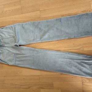 Ljusblåa Juicy couture byxor - Supermjuka ljusblå mjukisbyxor från Juicy Couture i storlek Xs med bred resår i midjan och snörning. Byxorna har raka ben och två bakfickor med lock och silvriga knappar. Inga defekter!!  Kontakta mig om du har några funderingar!!❤️