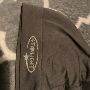 Mörkgrå mössa Starlight - Snygg mörkgrå mössa från Starlight med broderad logga och stjärndetalj på kanten. Enkel och stilren design som passar perfekt till kalla dagar. Mjuk och stretchig, tillverkad i bomullsmix för skön komfort.